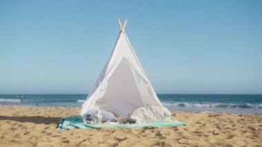 Sandy Beach 'teki romantik yemek için arka planı kopyala. Açık mavi gökyüzünün altında romantik bir gün batımı. Okyanus sahilinde beyaz çadır ve yumuşak yastıklarla romantik bir randevu. Plaj kafe konsepti 4K