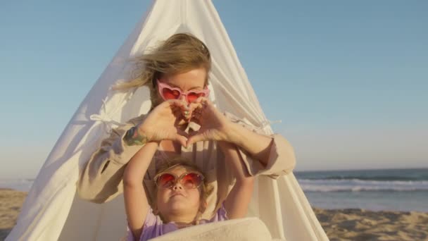 近距离观察年轻女子和小女孩的画像 他们表现出心脏的迹象 用手做记号 感受爱情 在海滩上微笑 爱的证明 快乐的家庭 良好的关系 — 图库视频影像