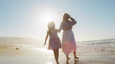 Annenin sevimli mutlu kızıyla kumsalda koşuşan sinematik siluetleri. Çocuk yaz tatilinde seyahat etmeyi hayal ediyor. Kaygısız kız annesiyle okyanusta eğleniyor. Mutlu aile 4K