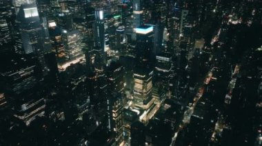 Geceleri uçsuz bucaksız New York manzarası. Muazzam bir gece şehri manzarayı aydınlatıyor. Hava karardıktan sonra gökdelenlerdeki iş ofisleri. Yukardan nefes kesici New York manzarası, USA 4K hava durumu