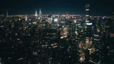 Muazzam bir gece şehri manzarayı aydınlatıyor. Hava karardıktan sonra gökdelenlerdeki iş ofisleri. New York 'un nefes kesici manzarası, ABD 4K hava sahası. Geceleri uçsuz bucaksız New York manzarası