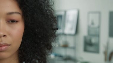 İnsanlar, genç çoklu kıvırcık modelin yarı yüz portresini kapalı gözlerle kapatıyor. Oldukça karışık ırk kızı gözlerini açıyor ve bulanık fotokopi arka planında modern dairede kameraya bakıyor.