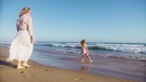 儿童梦的概念 金色落日下快乐的小女孩 孩子们和妈妈在海上玩得很开心快乐家庭联系的概念 爱的家庭关系 在沙滩上被海浪冲走的女孩 — 图库视频影像