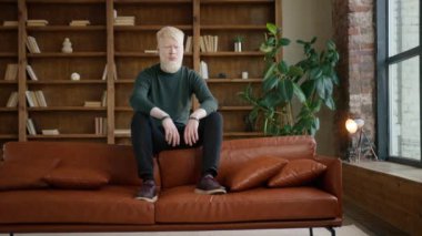 Albino işadamı ofiste koltukta oturuyor. Sıradan bir adam yalnız başına üzgün hissediyor. Depresyondaki adam gözlerini kapatıyor. Modern çatı katında poz veren erkek model. Genç adam finansal krizi düşünüyor. 