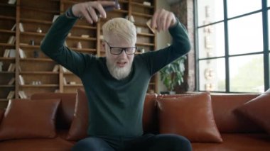 Albino işadamı ofisteki akıllı telefondan kötü haberler okuyor. Üzgün CEO koltukta otururken el kol hareketi yapıyor. Endişeli adam derin nefes alıyor. Genç girişimci iş yerinde stres hissediyor