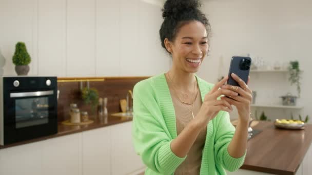 Leende Afroamerikansk Kvinna Står Modernt Kök Med Hjälp Smart Telefon — Stockvideo