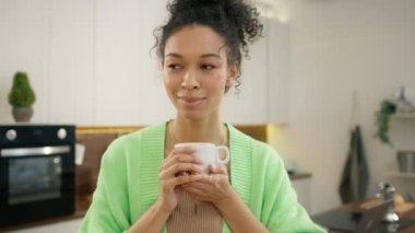 Evde ağır çekimde kahve içen çok ırklı çekici bir bayan. Modern mutfakta çay içen iki ırklı kadının portresi. Sabahları elinde çay tutan gülümseyen bir kadın.