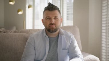 Güneşli bir günde oturma odasında gülümseyen orta yaşlı bir adamın portresi. RED kamerada yavaş çekim sineması. Yaşam tarzı kavramı, başarı, baba, başarılı girişimci iş sahibi.