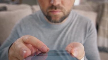 Ağır çekim erkek parmakları modern akıllı telefon ekranı 4K 'ye dokunuyor. Mobil uygulamalardaki cep telefonu cihazındaki sinemayı kapatan adam. İnternette film izlemek için internet kütüphanesinde film videosu taranıyor