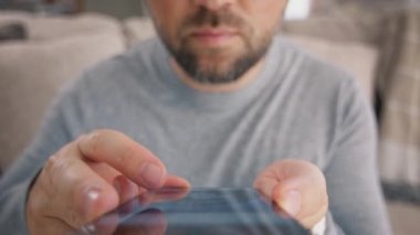 Sakallı adam cep telefonu ekranına bak ve sosyal ağlara bak. Yetişkin bir erkek cep telefonuyla uygulama okuyor. 30 'lu yaşlardaki hippi parmakları kapalı mekanda cep telefonuyla sohbet ediyor. Cep telefonu 4K 'de yaşam