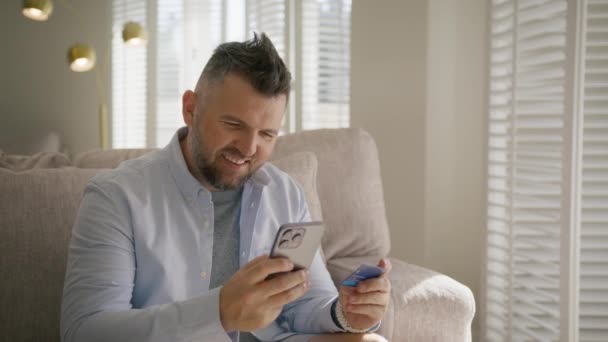 Szczęśliwy Facet Kupuje Online Rzuca Kartą Powietrze Mężczyzna Kupuje Smartfonie — Wideo stockowe
