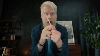 Ciddi bir albino girişimcisi çevrimiçi görüntülü konuşma sırasında iş arkadaşlarıyla konuşuyor. Sinirli iş adamı video konferansında girişimin planını açıklıyor. Saldırgan CEO ofiste kameraya el hareketi yapıyor. 