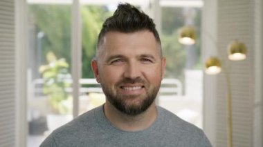 Gülümseyen sakallı, olgun, profesyonel iş adamı 40 'larında kameraya bakıyor. Kendinden emin, yakışıklı, zeki, genç, yetişkin girişimci, lider, evde poz veren bir yönetici. Yüze yakın iş portresi 4K çekim