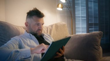 Evde çalışan tablet cihaz ekranına bakarak çevrimiçi dijital verileri analiz eden ve piyasa finansmanı sağlayan konsantre iş adamı. Sinematik çekim: Olgun girişimci günlük ev 4K 'de çalışıyor.