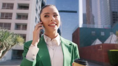 Başarılı bayan CEO hücresel konuşma sırasında gülümsüyor. Lüks elbiseli genç iş kadını metropolitan şehrindeki finans bölgesinde konuşmak için cep telefonu kullanıyor.