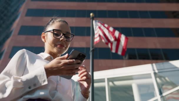 Mujer Bonita Mirando Teléfono Móvil Con Bandera Ondeante Estados Unidos — Vídeos de Stock