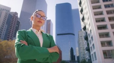 Resmi gömlekli şık bayan patron kadın lider kollarını kavuşturup şirket çalışanlarının kameralarına bakıyor. Millennial 20s başarılı güçlü iş kadını şehir merkezinde açık havada duruyor.