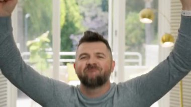 Şık saç stili olan sanatçı komedyen aptalca hareket ediyor ve dans ediyor. Yakışıklı adam kameraya bakıp gülümsüyor. Komik erkek, başarı piyangosunu kazanırken surat asıyor. Mutlu, etkileyici adam 80 'lerin hareketini yapıyor.