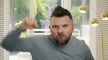 Komik olgun erkek müzik dinler, elleriyle el sallar, evdeki oturma odasında dans eder. Komik, genç, komik, komik adam aptalca dans hareketleri yapıyor. Parti enerjisi 4K. Espri konsepti