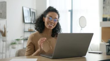 İçerideki laptop ekranına bakan mutlu çok ırklı kadının portresi. İnternette sohbet eden gözlüklü şık bir iş kadını. Çevrimiçi görüşme ya da eğitim için bilgisayar kullanan pozitif genç iş kadını