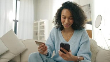 Çok yönlü gülümseyen, kredi kartına bakan, seyahat rezervasyonu yapmak için akıllı telefon dokunmatik ekranına kişisel veriler yazan çok ırklı bir kadın. Çevrimiçi dükkanda cep telefonu taksitlerini kullanan mutlu kadın müşteriler.