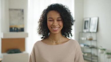 Modern kentsel apartman arka planında modern şık kıyafetler giymek. Gerçek insan dizisi 4K. Güzel, şık, biseksüel Afrikalı Amerikalı kadının portresi. Kameraya gülümsüyor. Kendinden emin görünüyor.