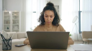 Dizüstü bilgisayarda farklı renkte yazı yazan, çağdaş evde bilgisayar üzerinde çalışan bir kadın. İş kadını. Genç Afro-Amerikan odaklı kadın yönetici yönetici iş kadını. İç işlerinde masa başında oturuyor.
