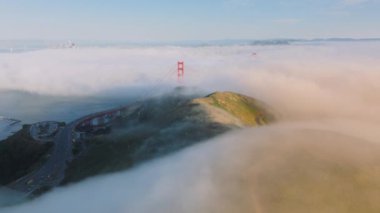 Bulut oluşumlarının resimli görüntüsü Golden Gate Köprüsü ve San Francisco manzarası, Kaliforniya, ABD 'yi sardı. Güneş doğarken yoğun sisin içinden çıkan kırmızı köprünün hava görüntüsü, 4K görüntü. 