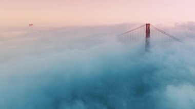 Golden Gate Köprüsü 'nün gün doğumunda San Francisco, Kaliforniya, ABD' de sisli bir görüntüsü. Sis Karl kırmızı köprünün altında sürükleniyor. Amerika 'nın ünlü simgesi. Kapı köprüsü sabah yoğun sisi delip geçiyor.
