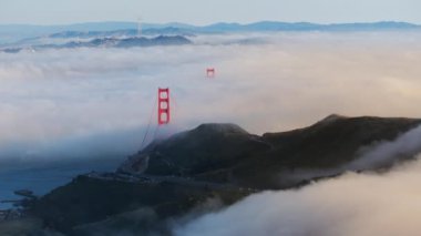 Sis bulutlarının hava görüntüleri Golden Gate Köprüsü 'nü çevreledi, San Francisco, Kaliforniya, ABD. San Francisco köprüsünün sabah manzarası ve sisin içindeki dağlar. Zaman aşımında sis manzarası, 4k görüntü 