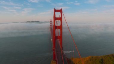 San Francisco, California, ABD 'deki bulutlu Golden Gate Köprüsü' nde hareket eden arabaların panoramik görüntüsü. Sabahki bulut oluşumunun insansız hava aracı görüntüleri kırmızı köprüyü, körfez ve şehri kapsıyor. 4K görüntü. 
