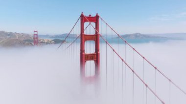 Golden Gate Köprüsü 'nün kuş bakışı manzarası sis bulutlarının üzerinde yükseliyor, San Francisco, California, ABD. San Francisco Körfezi 'nin resimli manzarası ve sabah sisiyle kaplı dağlarla çevrili 4k görüntü. 