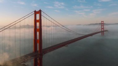 Golden Gate Köprüsü 'nden San Francisco, Kaliforniya' ya giden arabaların hava görüntüsü. Sabah sisinde 101. yolda giden otomobillerin yukarıdan çekimleri. San Francisco ufuk çizgisi gün doğumunda, 4k görüntü 