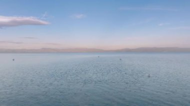 Doğa arkaplan gökyüzü suya yansıyor. Alacakaranlıkta ayna gölünün yukarısındaki ahşap kayıkhanenin huzurlu arka planı. Geriye doğru uçarak mavi Tahoe gölünün üzerinde ufukta dağlarla birlikte tersten uçuyor.