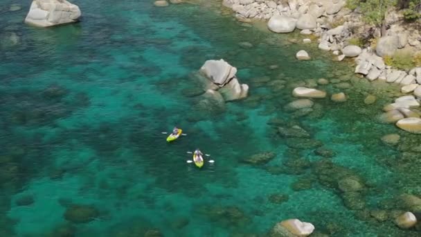 场景无人机拍摄清晰透明的茶色蓝色水4K 从空中俯瞰着皮划艇 划向塔荷湖岸边的大石头 周末或假期享受大自然的人的日常开销 — 图库视频影像