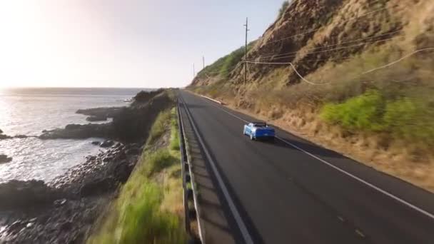 山道で青いスポーツカーに乗るハッピーな観光客 未来のアウトドアアドベンチャー エアリアルショット高価な青い高級コンバーチブルバケーション車は 晴れたクリーンな道路ハイウェイ島を運転します — ストック動画