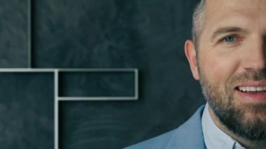 Gülümseyen yakışıklı, sakallı profesyonel iş adamı kameraya bakıyor. Mutlu kendinden emin orta yaşlı yetişkin girişimci, gri arka planda poz veren lider yönetici. Yarı yüz iş portresini kapat