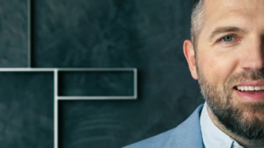 Gülümseyen yakışıklı, sakallı profesyonel iş adamı kameraya bakıyor. Mutlu kendinden emin orta yaşlı yetişkin girişimci, gri arka planda poz veren lider yönetici. Yarı yüz iş portresini kapat