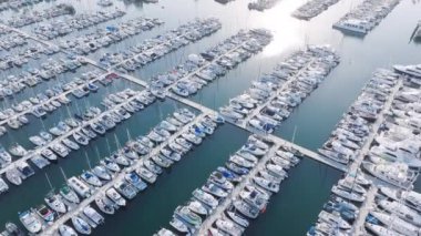 Santa Barbara Limanı üzerinde lüks yatlarla uçan insansız hava aracı, Kaliforniya, ABD. Şehir limanına demirlemiş özel yelkenlilerin yukarıdan çekimleri. Tekneler küçük limana yanaştı. Point Castillo 'dan görüntü, 4K görüntü