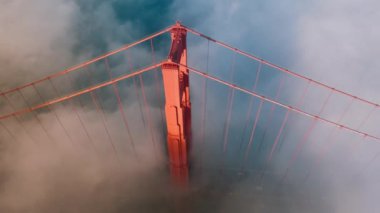 San Francisco, ABD 4K 'deki Golden Gate köprüsünün kırmızı kulesinin etrafında sihirli sis bulutunun destansı hareketli arka planı. Golden Gate Köprüsü 'nün nefes kesici havası gün batımında ya da gün doğumunda altın gün ışığında aydınlanır..