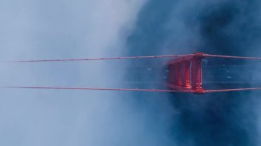Kırmızı Golden Gate Köprüsü 'nden geçen araçlar. B rulosu Amerikan tarihi 4K. San Francisco 'daki kırmızı Golden Gate köprüsünün etrafında uçan dramatik mavi sis bulutu kuruluyor.