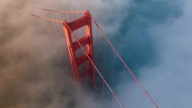 San Francisco, ABD 4K 'deki Golden Gate köprüsünün kırmızı kulesinin etrafındaki sihirli sis bulutunun B dönüşü. Golden Gate Köprüsü 'nün nefes kesici havası gün batımında ya da gün doğumunda altın gün ışığında aydınlanır.