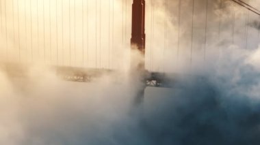 Golden Gate Köprüsü 'ndeki dramatik bulut manzaralı yol. Kırmızı köprü, ABD 'den geçen arabaların etrafında dönen yoğun sis. Deniz mavisi turuncu bulutların destansı havası manzaralı altın günbatımı ışığında hızla sürükleniyor. USA 4K