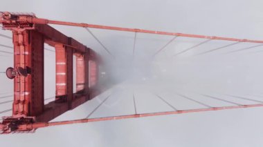 Parlak güneşli bir günde, yukarıdaki yüksek kırmızı köprüden alçalıyoruz. Yoğun siste, San Francisco 'da yolda giden arabaların üzerinden kayıyor. ABD manzaralı beyaz bulutlu Golden Gate Köprüsü 'nde trafik
