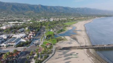 Santa Barbara kıyı şeridi kuşbakışı manzaralı şehir silueti, California, ABD. İHA yeşil dağları çevreleyen tatil köyü boyunca uçuyor. Pasifik Okyanusu 'ndaki kumlu sahilin havadan çekilmiş görüntüsü, 4K görüntü.