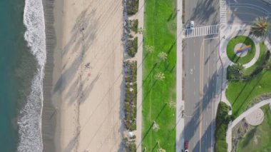 Santa Barbara plajı ve trafik manzarası, Kaliforniya, ABD. Pasifik Okyanusu 'ndaki dalgaların insansız hava aracı görüntüsü. Arabalar deniz kenarında şehir yolunda gidiyor. Sahilde büyüyen palmiye ağaçları, 4k görüntü. 