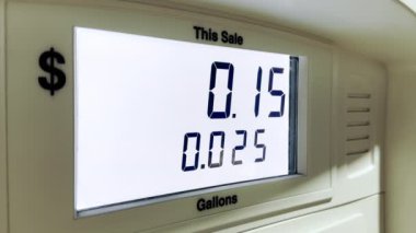 Yakıt dağıtıcısının ekranında sürücünün arabasına doldurulan yakıt miktarı ve maliyetini gösteren rakamlar var. Ekran beyaz ışıkla aydınlatılır..