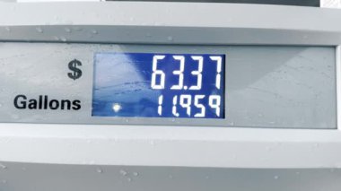 Devriye istasyonunda mavi dijital benzin göstergesi. Yakıt miktarı galon ve dolar. Benzin fiyatları sayacı, yakın plan. Yakıt tanka girdikçe ekranda galon başına fiyat artar.