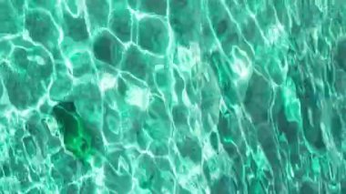 Su yüzeyindeki güneş ışığından oluşan dalgalanmaların yakınlaşması. Dikey turkuaz ve berrak deniz suyu. Taşlar okyanusun dibinde yatıyordu. Kopya alanı ile kusursuz doğal arkaplan, 4k görüntü