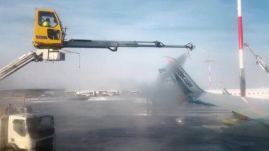 LOS ANGELES, CALIFORNIA, ABD-30 ECTOBER 2023: Teknik işçiler uçak kanadına krema önleyici sıvılar püskürtüyorlar. Westjet uçakları uluslararası havaalanından kalkmadan önce buz çözücü tedavisi görüyor.